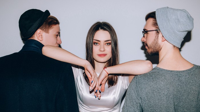 1177417560 Polyamorous relationship. Modern partnership love. Confident woman dominating over two men.