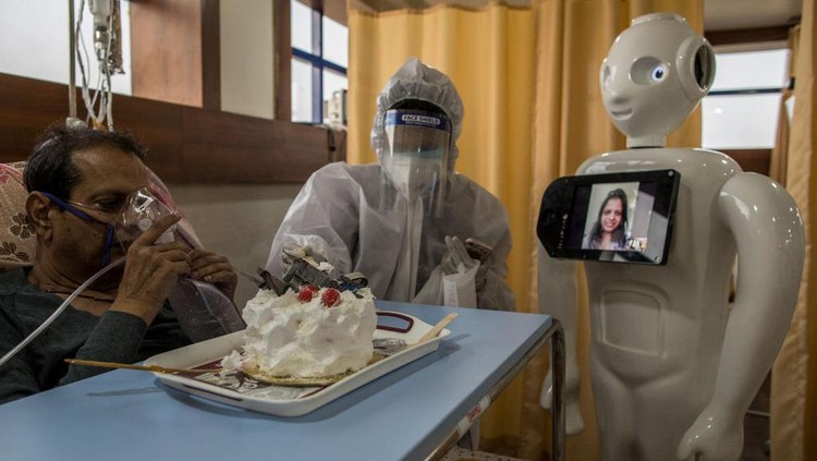 NEW DELHI, INDIA - DECEMBER 05: A Covid-19 patient connects with a family member with the assistance a robot as he receives a cake on his birthday on December 5, 2020 in New Delhi, India. The 