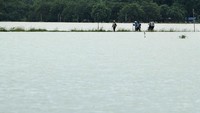 Petani melintasi area sawah yang terendam banjir di kawasan Indramayu, Jawa Barat, Selasa (5/1/2021).