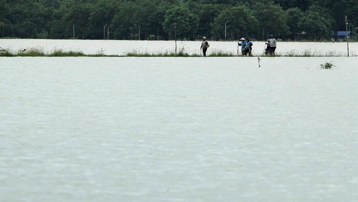 Terendam Banjir, Sawah di Indramayu Berubah Jadi Kolam Dadakan Warga melintasi banjir di Desa Widasari, Indramayu, Jawa Barat, Selasa (5/1/2021). Ratusan rumah di desa tersebut terendam banjir setingggi 50 cm hingga satu meter akibat luapan sungai Cibuaya. ANTARA FOTO/Dedhez Anggara/rwa.