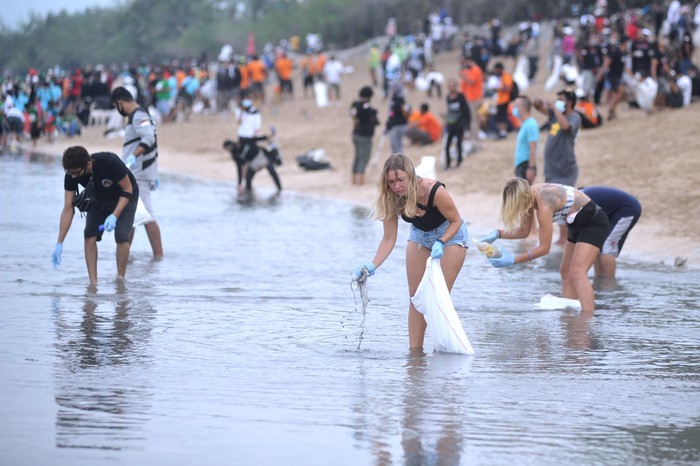 Relawan membersihkan sampah yang berserakan saat mengikuti aksi bersih sampah di Pantai Kuta, Badung, Bali, Rabu (6/1/2021). Kegiatan yang diikuti ratusan orang dari berbagai unsur masyarakat tersebut dilakukan untuk membersihkan sampah kiriman yang terbawa arus gelombang laut dan terdampar kawasan Pantai Kuta yang mengganggu aktivitas warga serta wisatawan. ANTARA FOTO/Fikri Yusuf/aww.