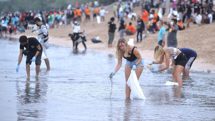 Relawan membersihkan sampah yang berserakan saat mengikuti aksi bersih sampah di Pantai Kuta, Badung, Bali, Rabu (6/1/2021). Kegiatan yang diikuti ratusan orang dari berbagai unsur masyarakat tersebut dilakukan untuk membersihkan sampah kiriman yang terbawa arus gelombang laut dan terdampar kawasan Pantai Kuta yang mengganggu aktivitas warga serta wisatawan. ANTARA FOTO/Fikri Yusuf/aww.