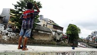 Seorang anak bermain layang-layang di atas dinding turap Kali Cideng, Jalan Tanah Sereal, Tambora, Jakarta Barat, Rabu (6/1/2021).