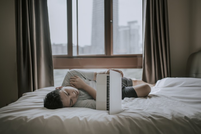 Young man resting on the floor whit a book on his face while enjoying the sun coming through the window. Concept of stay at home, freedom, boredom...