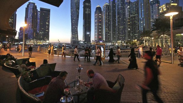 FILE - In this May 1, 2015, file photo, two men play backgammon while smoking a shisha water pipe at a restaurant overlooking the canal and the Dubai Marina neighborhood in Dubai, United Arab Emirates. Dubai again has loosened laws governing alcohol sales and possession as the sheikhdom tries to claw its way out of an economic depression worsened by the coronavirus pandemic. The virus worsened an already-gathering economic storm engulfing the emirate, which has seen mass layoffs thin the ranks of its foreign workforce and empty homes across its vast real-estate sector even amid slight signs of recovery. (AP Photo/Kamran Jebreili, File)