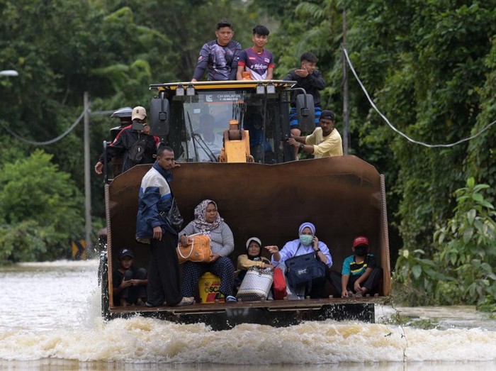 Residents ride a digger vehicle through floodwaters following heavy monsoon downpour in Lanchang, Malaysias Pahang state on January 6, 2021. (Photo by Mohd RASFAN / AFP)