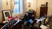 Richard Barnett, seorang pendukung Presiden AS Donald Trump duduk di dalam kantor Ketua DPR AS Nancy Pelosi.