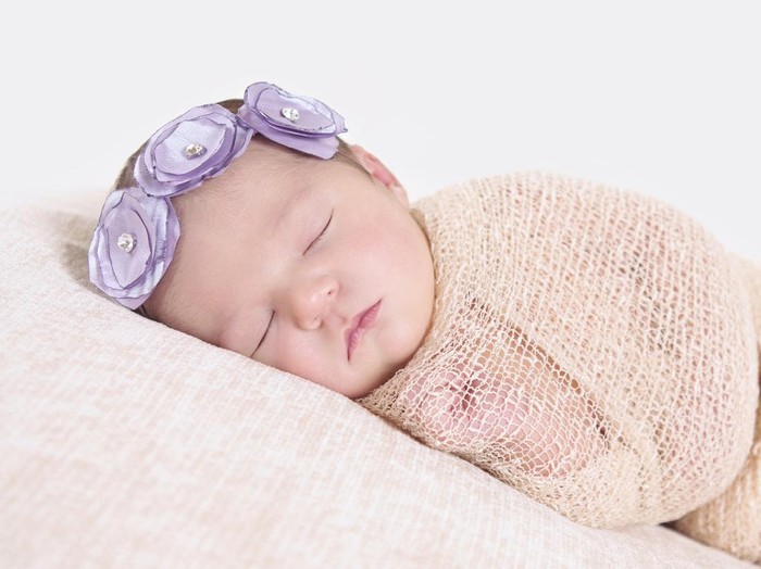 1040213716 Beautiful mother kissing here little cute baby on her palm. Mother take care her little girl at home. One week newborn girl.