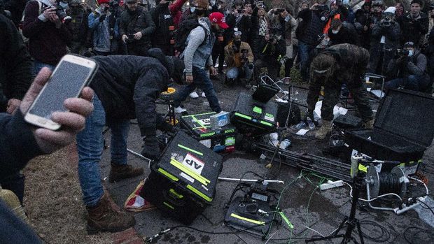 Demonstrators break TV equipment outside the the U.S. Capitol on Wednesday, Jan. 6, 2021, in Washington, during a chaotic protest aimed at thwarting a peaceful transfer of power. (AP Photo/Jose Luis Magana)