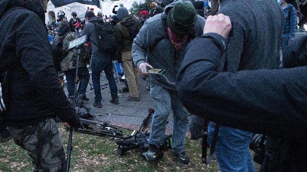 Demonstrators break TV equipment outside the the U.S. Capitol on Wednesday, Jan. 6, 2021, in Washington. (AP Photo/Jose Luis Magana)