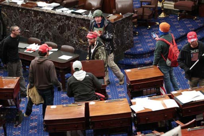 WASHINGTON, DC - JANUARY 06: A pro-Trump protester carries the lectern of U.S. Speaker of the House Nancy Pelosi through the Roturnda of the U.S. Capitol Building after a pro-Trump mob stormed the building on January 06, 2021 in Washington, DC. Congress held a joint session today to ratify President-elect Joe Bidens 306-232 Electoral College win over President Donald Trump. A group of Republican senators said they would reject the Electoral College votes of several states unless Congress appointed a commission to audit the election results.   Win McNamee/Getty Images/AFP