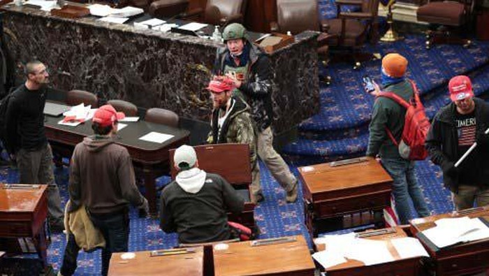 WASHINGTON, DC - JANUARY 06: A pro-Trump protester carries the lectern of U.S. Speaker of the House Nancy Pelosi through the Roturnda of the U.S. Capitol Building after a pro-Trump mob stormed the building on January 06, 2021 in Washington, DC. Congress held a joint session today to ratify President-elect Joe Bidens 306-232 Electoral College win over President Donald Trump. A group of Republican senators said they would reject the Electoral College votes of several states unless Congress appointed a commission to audit the election results.   Win McNamee/Getty Images/AFP