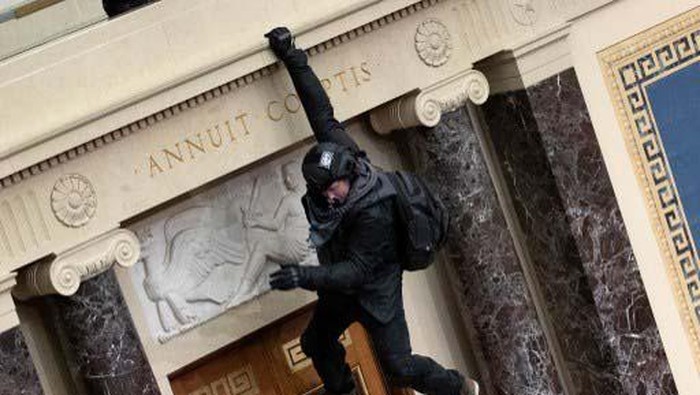 Melihat Lagi Aksi Pendukung Trump Panjat Gedung Capitol AS WASHINGTON, DC - JANUARY 06: A pro-Trump protester carries the lectern of U.S. Speaker of the House Nancy Pelosi through the Roturnda of the U.S. Capitol Building after a pro-Trump mob stormed the building on January 06, 2021 in Washington, DC. Congress held a joint session today to ratify President-elect Joe Biden's 306-232 Electoral College win over President Donald Trump. A group of Republican senators said they would reject the Electoral College votes of several states unless Congress appointed a commission to audit the election results. Win McNamee/Getty Images/AFP