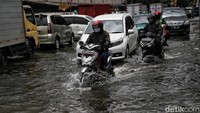 Pemotor yang melintas kawasan tersebut berusaha menerobos genangan air yang tak kunjung surut.