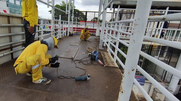 Pasukan kuning Dinas Bina Marga DKI Jakarta perbaiki JPO Matraman, Jakarta Timur.