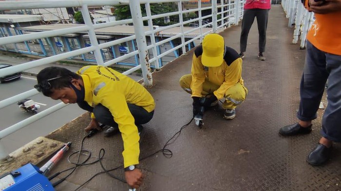 Pasukan kuning Dinas Bina Marga DKI Jakarta perbaiki JPO Matraman, Jakarta Timur.