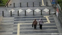 Warga saat melintas di trotoar kawasan Jalan Jend. Sudirman, Jakarta Pusat, Kamis (07/01/2021).