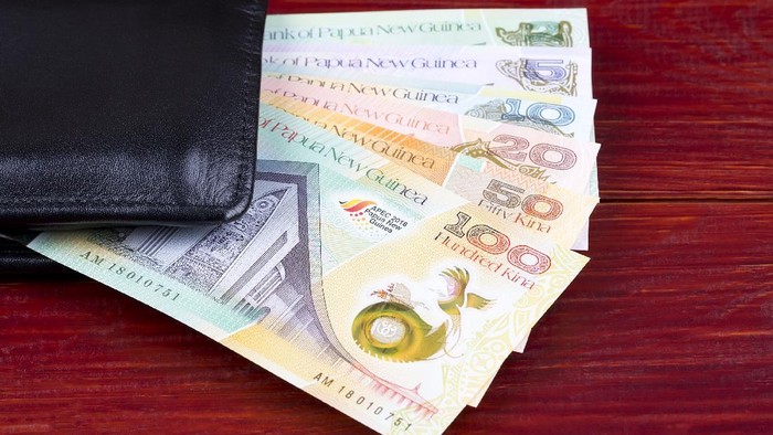 Money from Papua New Guinea in the black wallet on a wooden background