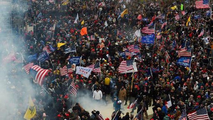Supporters of US President Donald Trump enter the US Capitol as tear gas fills the corridor on January 6, 2021, in Washington, DC. - Demonstrators breeched security and entered the Capitol as Congress debated the a 2020 presidential election Electoral Vote Certification. (Photo by Saul LOEB / AFP)
