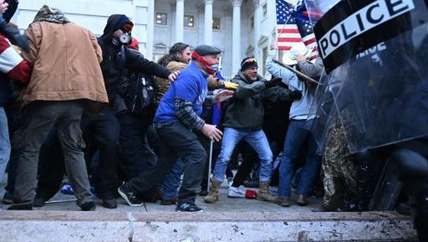 Supporters of US President Donald Trump enter the US Capitol as tear gas fills the corridor on January 6, 2021, in Washington, DC. - Demonstrators breeched security and entered the Capitol as Congress debated the a 2020 presidential election Electoral Vote Certification. (Photo by Saul LOEB / AFP)