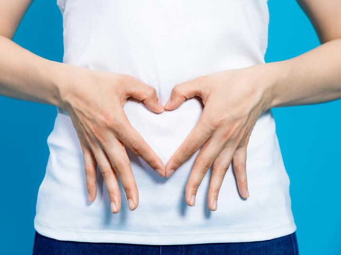 Ilustrasi hamil muda young woman who makes a heart shape by hands on her stomach.