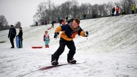  Seorang warga bermain snowboard di Queens Park, Glasgow, Skotlandia, Kamis (7/1/2021) waktu setempat. Jeff J Mitchell/Getty Images