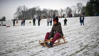 Warga memanfaatkan musim dingin bersalju untuk menghabiskan waktu dengan bermain seluncur. Jeff J Mitchell/Getty Images
