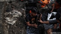 Petugas harus nyemplung ke got yang airnya berwarna hitam untuk mengeruk lumpur.