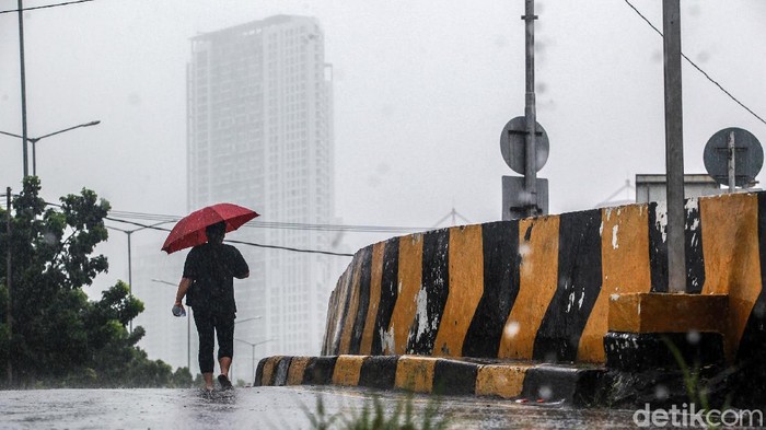 Puncak Musim Hujan Diperkirakan Sampai Februari Warga beraktivitas di bawah guyuran air hujan di Kemayoran, Sabtu (9/1/2021). Badan Meteorologi, KliÂmatologi dan Geofisika (BMKG) memperkirakan wilayah Indonesia saat ini sudah memasuki puncak musim hujan. Periode ini akan bertahan hingga Februari mendatang.