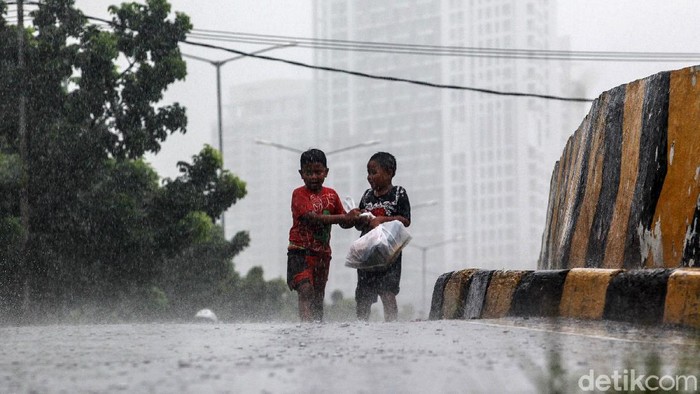 Puncak Musim Hujan Diperkirakan Sampai Februari Warga beraktivitas di bawah guyuran air hujan di Kemayoran, Sabtu (9/1/2021). Badan Meteorologi, Klimatologi dan Geofisika (BMKG) memperkirakan wilayah Indonesia saat ini sudah memasuki puncak musim hujan. Periode ini akan bertahan hingga Februari mendatang.