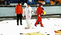 Petugas menyemprotkan cairan disinfektan pada kantong-kantong jenazah berisi potongan tubuh korban jatuhnya pesawat Sriwijaya Air SJ182, di dermaga JITC 2, Tanjung Priok, Jakarta, Minggu (10/01/2022).