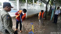Dua warga dihukum membersihkan jalan karena melanggar aturan PPKM.