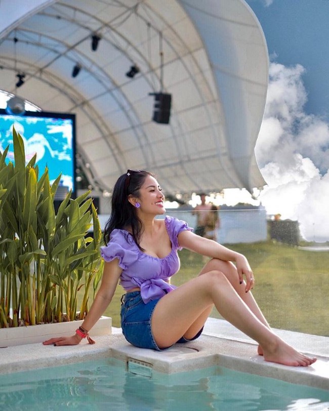 Memasang pose di pinggir kolam renang, ibu satu anak ini bergaya girlie sekaligus seksi berbalut blouse aksen ruffle dan short jeans. Foto: Instagram/@mozawahyu, @nindyparasadyharsono