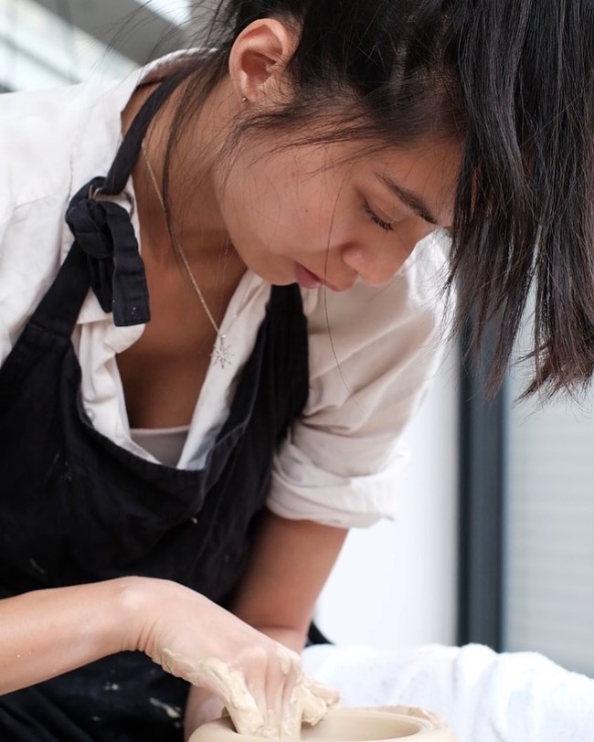 Biasa tampil glamour dengan baju-baju desainer, penonton pun bisa melihat penampilan sederhananya dengan apron dan kaus ketika mengolah tanah liat. Foto: Instagram @shenyueding/ @supperceramics