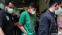 Askara tampak mengenakan baju tahanan berwarna hijau saat berjalan menemui awak media. Pool/Palevi S/detikFoto