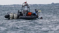Penyelam mengangkat serpihan atau benda dari pesawat ke atas permukaan laut.