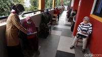 Warga tampak menjaga jarak saat antre penyaluran bantuan sosial tunai (BST).