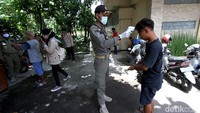 Petugas memeriksa suhu tubuh salah satu warga yang terjaring razia masker di Solo.