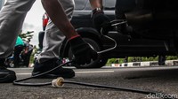 Petugas tampak memasukan alat uji emisi ke knalpot mobil.