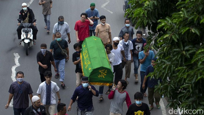 Warga turun ke jalan untuk mengiringi jenazah yang akan dimakamkan di kawasan Jakarta. Pandemi tak membuat tradisi mengiringi jenazah itu ditinggalkan warga.