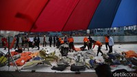 Terlihat anggota Polairud berbondong-bondong menurunkan serpihan pesawat dan kantong jenazah dari kapal. Objek tersebut langsung diletakkan di terpal berisi puing-puing SJ182 yang sudah ditemukan sejak kemarin.