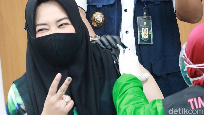 Risa Saraswati ikut kick off penyuntikan vaksin COVID-19 di RSKIA Kota Bandung. Novelis sekaligus YouTuber itu sempat mengacungkan dua jarinya saat disuntik.