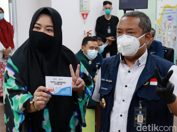 Risa Saraswati ikut kick off penyuntikan vaksin COVID-19 di RSKIA Kota Bandung. Novelis sekaligus YouTuber itu sempat mengacungkan dua jarinya saat disuntik.