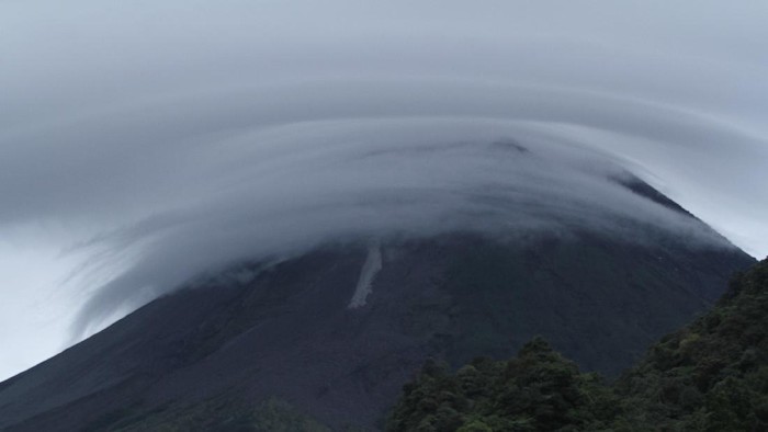 Awan Lentikular Selimuti Merapi Awan lentikular menutupi puncak Gunung Merapi saat Merapi mengeluarkan lava pijar, Kamis (14/1/2021). Begini potretnya.