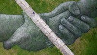 Seorang wanita berjalan di tengah-tengah mural rumput yang dibuat oleh seniman tanah Prancis Guillaume Legros, di Istanbul, Turki. Getty Images/Chris McGrath  