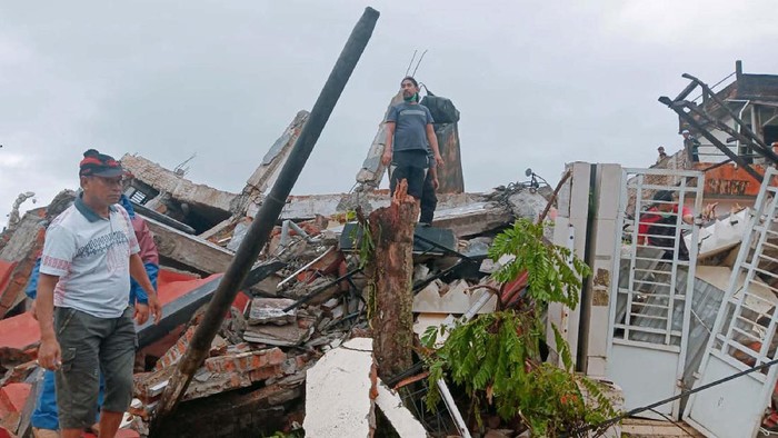 Residents inspect earthquake-damaged buildings in Mamuju, West Sulawesi, Indonesia, Friday, Jan. 15, 2021. A strong inland and shallow earthquake hit eastern Indonesia early Friday causing people to panic in parts of the countrys Sulawesi island and run to higher ground. (AP Photo/Rudy Akdyaksyah)