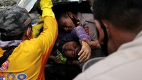 Petugas mengevakuasi korban yang terjepit bangunan di rumah sakit Mitra Manakarra yang runtuh akibat gempa bumi di Mamuju, Sulawesi Barat, Kamis (15/1/2021). 