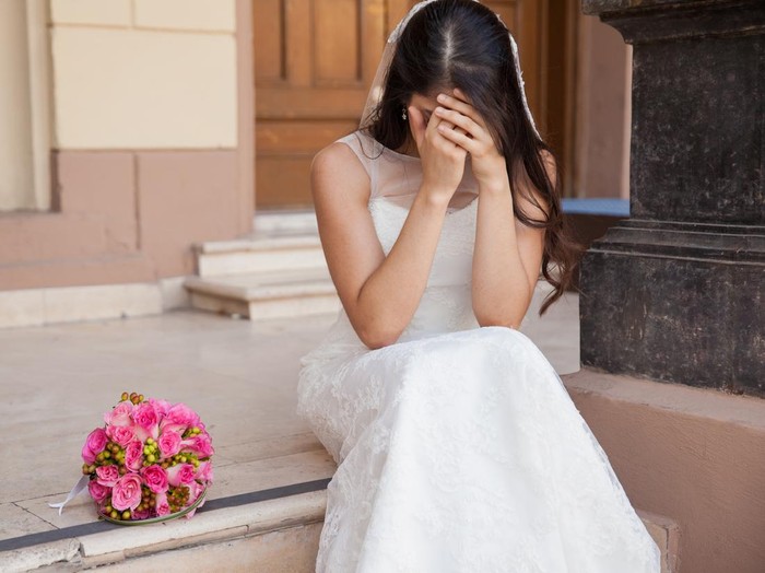 Hopeless bride crying outside a church after being stood up on her wedding day