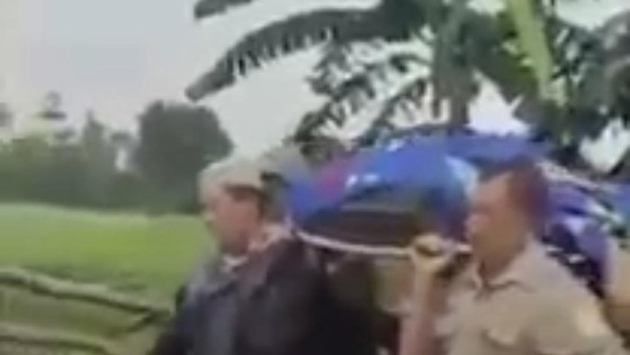 Jenazah digotong dengan tandu oleh warga ke rumah duka karena mobil ambulance tak bisa lewat akibat jalanan rusak parah