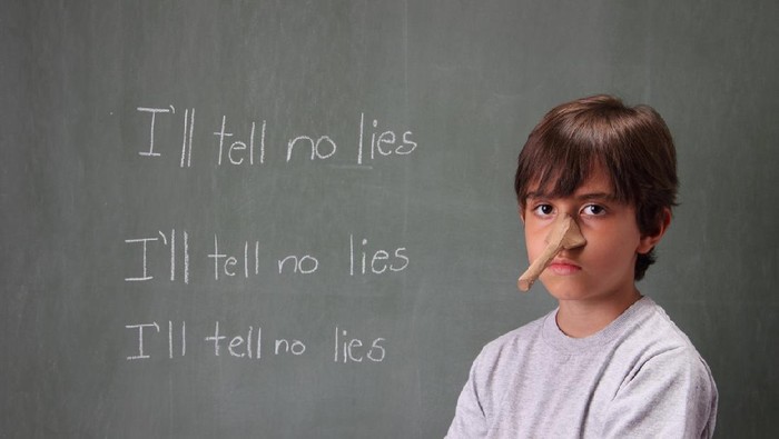 Kid with Pinocchio nose in front of blackboard